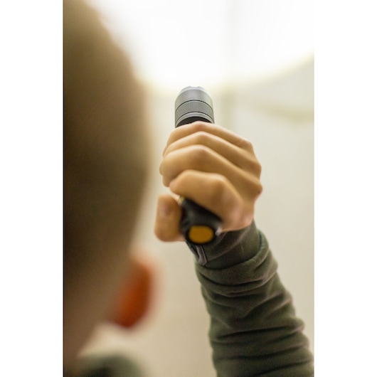 Photo of a person holding a STANLEY FMHT81511-0 flashlight, view focuses on the hand gripping the handle.