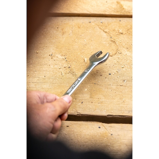 STANLEY FMMT13034-0 wrench held by hand on wooden surface, silver finish, open-end design.
