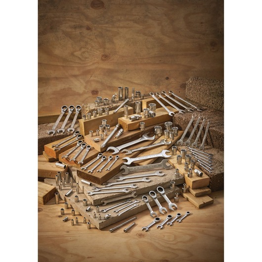 Various metal wrenches and sockets organized on wooden blocks with a plywood background.