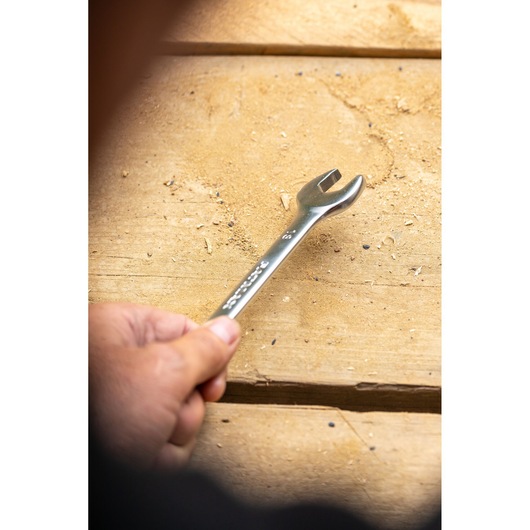 STANLEY FMMT13042-0 wrench held by hand on wooden surface, silver finish, photography side angle.