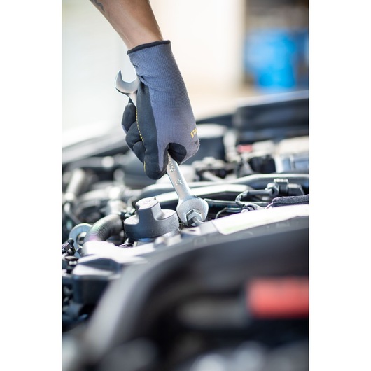 Stanley FMMT13066-0 wrench used by gloved hand on car engine, close-up photography.