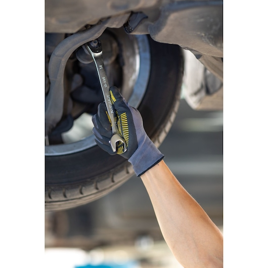 Photo of STANLEY FMMT13083-0 mechanic’s glove holding a wrench on a car undercarriage, automotive use.