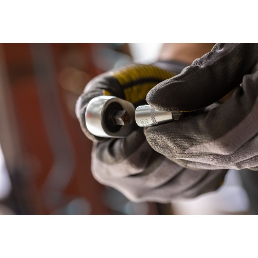Photo of STANLEY FMMT17186-0 socket wrench tool held by gloved hands, close-up view.