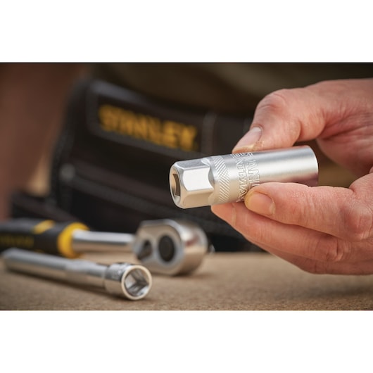 STANLEY FMMT17226-0 socket held in hand, with ratchet and extension tool on work surface.