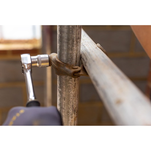 STANLEY FMMT17227-0 ratchet wrench in use tightening a metal scaffold clamp, close-up photography.