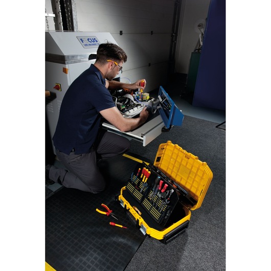 STANLEY FMST1-72383 toolbox with organized hand tools, open on the floor near technician repairing equipment.