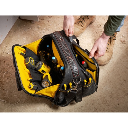 STANLEY FMST1-73607 tool bag with yellow interior, filled with tools, shown from above on jobsite floor.