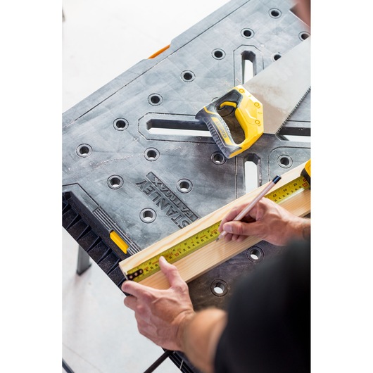 STANLEY FMST1-75672 workbench with hand saw and tape measure, wood being marked for cutting.