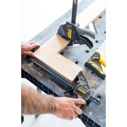 STANLEY FMST1-75672 woodworking clamp securing two wooden boards at a right angle on a workbench, close-up.