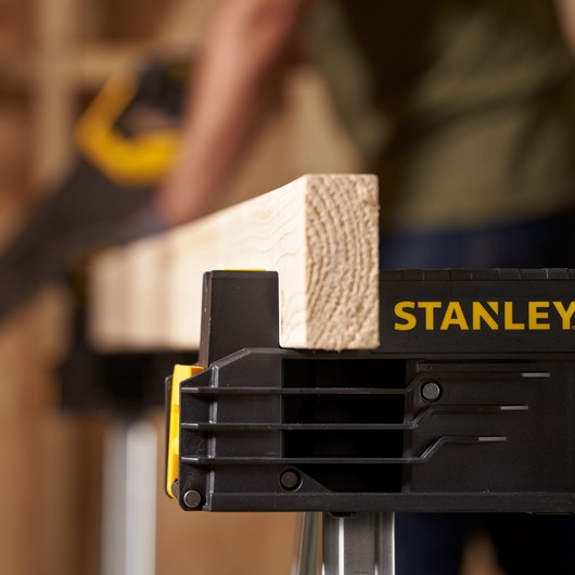 Photo of STANLEY FMST1-75763 sawhorse holding a wood plank, close-up view with logo visible.