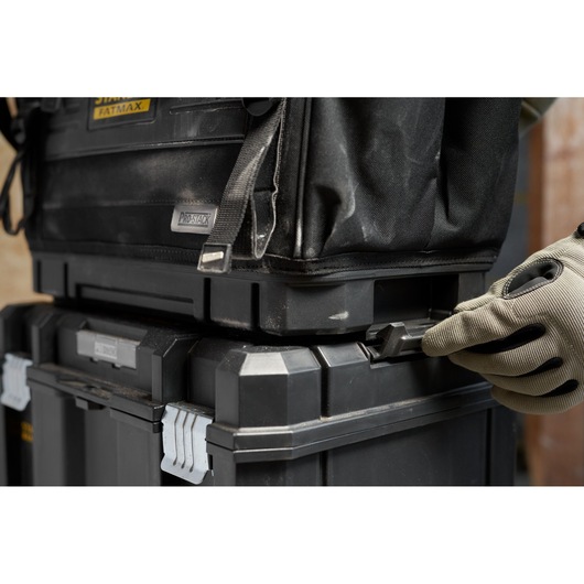 STANLEY FMST17626-1 stackable black toolboxes with side latch being handled, close-up angle.