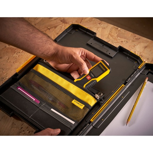 Photo of STANLEY FMST82721-1 tool case with yellow and black organizer, hand holding digital measuring tool.