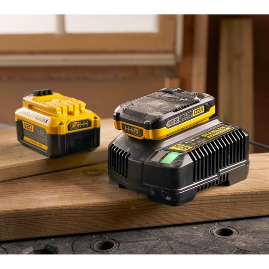 Photo of STANLEY SFMCB14 V20 lithium-ion battery and charger on wood, workshop background.