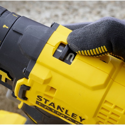 Photo of STANLEY SFMCD711C2K drill’s speed switch being adjusted, close-up view with gloved hand.
