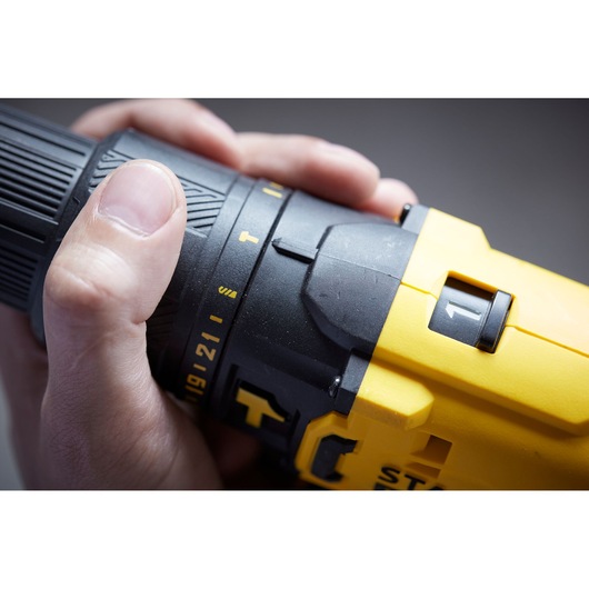 Close-up photo of STANLEY SFMCD711C2S drill settings dial in hand, showing yellow and black details.