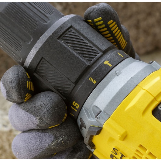 Photo of STANLEY SFMCD715C2K drill, close-up of hand adjusting torque settings, yellow and black casing.