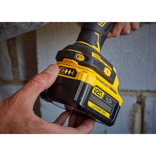 Photo of STANLEY SFMCD715M2K cordless drill with V20 4.0Ah lithium-ion battery being held near a wall.