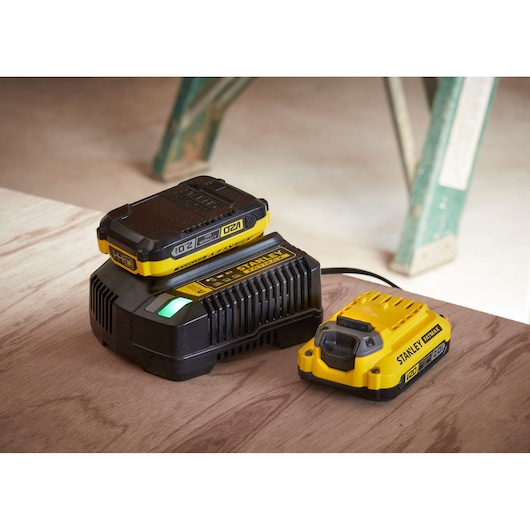 STANLEY SFMCD721D2K battery charger kit with two yellow and black 18V lithium-ion batteries on wooden surface.
