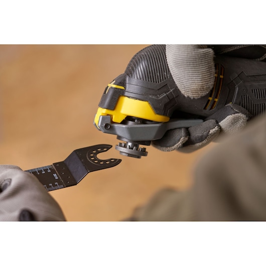 STANLEY SFMCE500B oscillating tool close-up with attachment being installed, photo of hands in gloves.