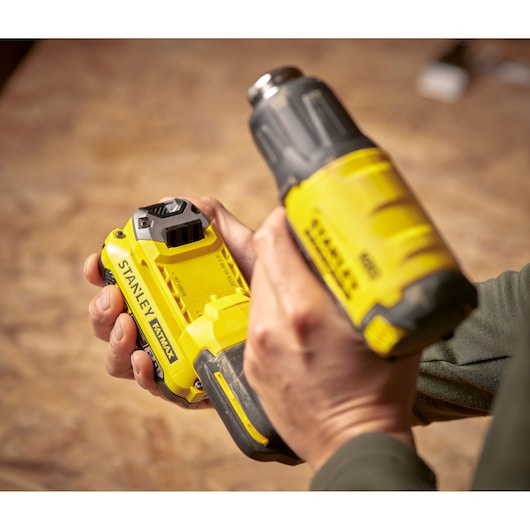 Photo of STANLEY SFMCE530B cordless power tool in use, yellow and black, close-up of hands holding tool.