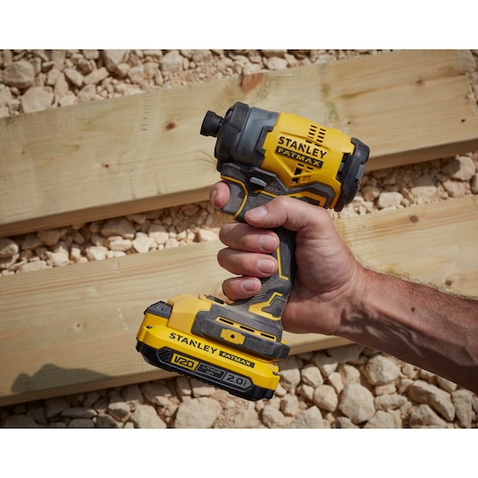 STANLEY SFMCF810D2K impact driver, yellow and black, handheld, shown outdoors on wood and gravel.