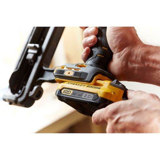 Photo of STANLEY SFMCN616B cordless nailer with V20 lithium-ion battery, close-up view in hand.