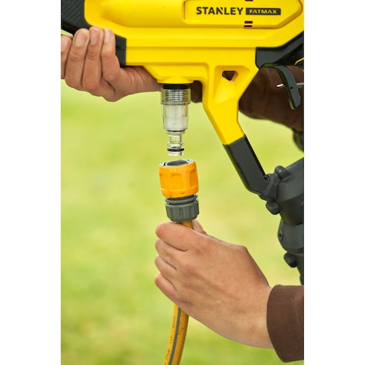 Photo of STANLEY SFMCPC93B connector being attached to yellow hose outdoors.