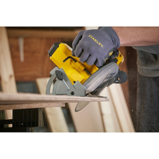 Stanley SFMCS500B circular saw in use, cutting wood, close side view, yellow and gray tool.