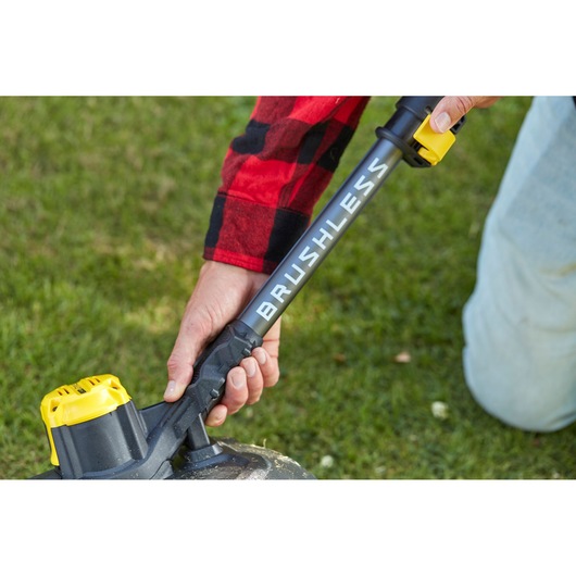 Stanley SFMCSTB933M brushless string trimmer with yellow battery, close-up on grass.