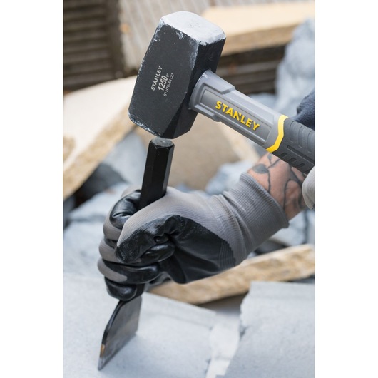 STANLEY STHT0-54127 sledge hammer being used with a chisel on stone, close-up view.