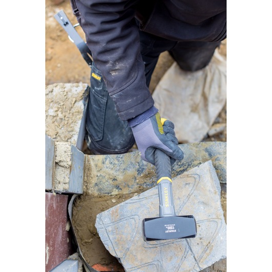 Photo of STANLEY STHT0-54128 club hammer with black and yellow handle used to break stone outdoors.