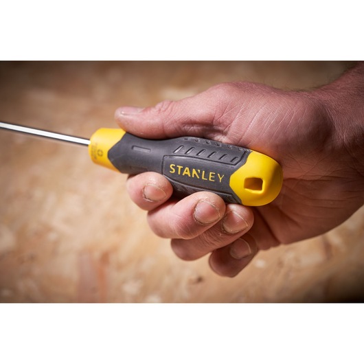 Photo of STANLEY STHT0-60358 screwdriver with yellow and black handle held in hand, close-up view.