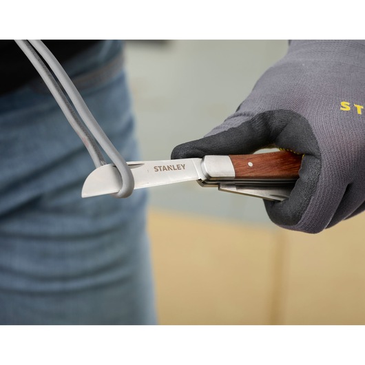 STANLEY STHT0-62687 pocket knife with wood handle cutting cable, close-up photography.