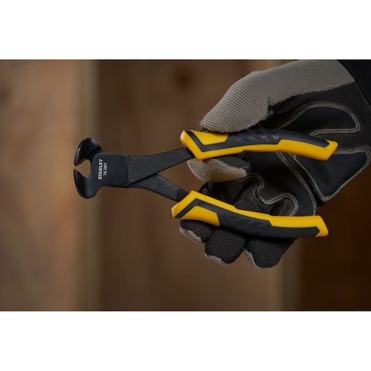STANLEY STHT0-75067 end cutting pliers with black and yellow handles, held in a gloved hand, side view.