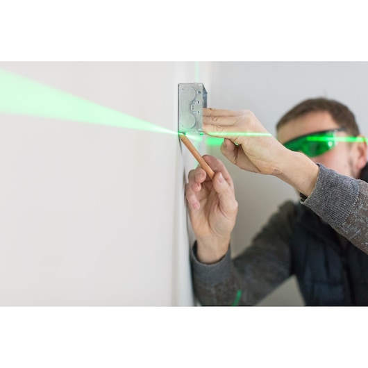 STANLEY STHT1-77367 laser level projecting green line on wall, used for marking position during installation.