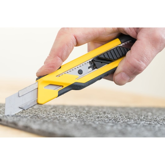 STANLEY STHT10266-0 utility knife close-up cutting carpet, yellow and black handle.