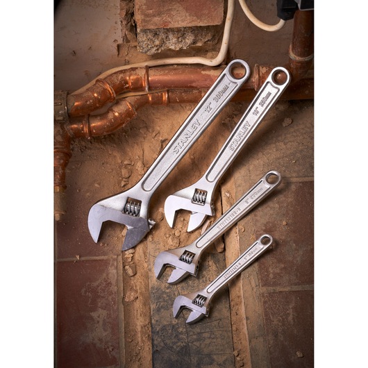 Stanley STHT13156-0 adjustable wrench set on construction site floor, four sizes visible.