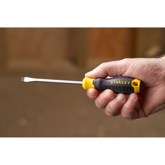 STANLEY STHT16146-0 flathead screwdriver with yellow and black handle, held in hand, side angle.