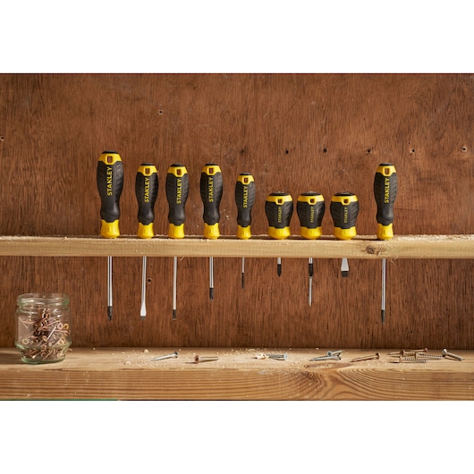 STANLEY STHT16154-0 screwdriver set with black and yellow handles, nine pieces on wooden shelf, front view.