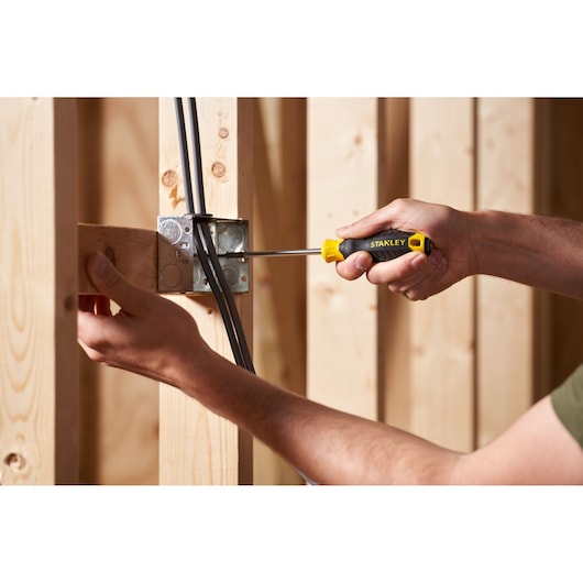 STANLEY STHT16163-0 screwdriver used to install wiring in a metal electrical box, close-up in construction setting.