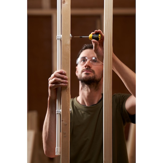 Photo of STANLEY STHT16196-0 screwdriver used by person installing a screw in wooden frame.