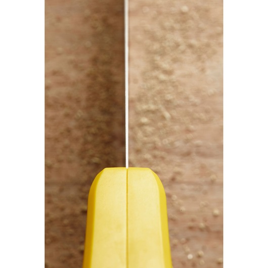 Photo of STANLEY STHT20351-1 hand saw with yellow handle, top view, on wood surface with sawdust.