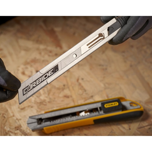 STANLEY STHT3-11825 utility knife with exposed carbide blade on wood surface, close-up angle.
