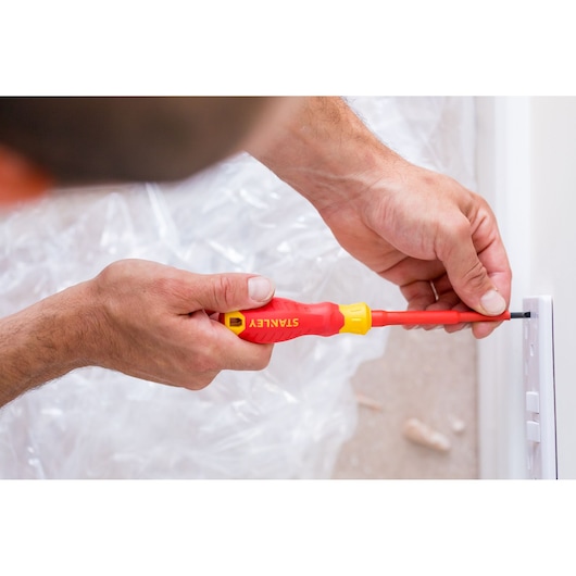STANLEY STHT60032-0 insulated screwdriver used for electrical work near a light switch.