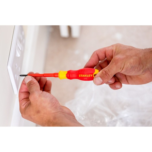 Stanley STHT60032-0 insulated screwdriver used on electrical outlet, close-up photo.