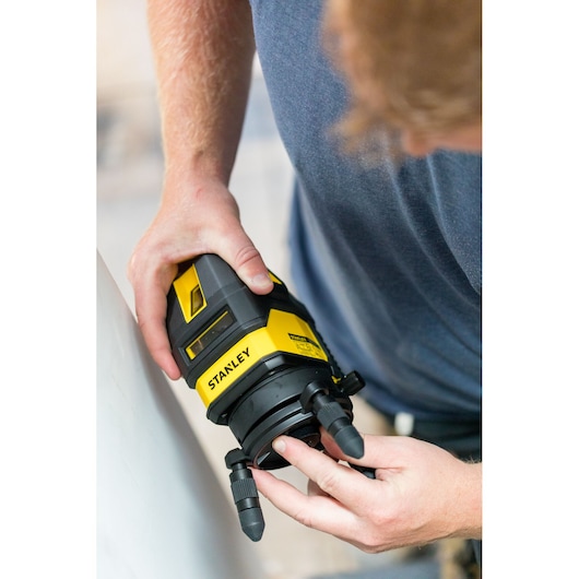 STANLEY STHT77514-1 laser level in use, black and yellow body, shown from above during adjustment.