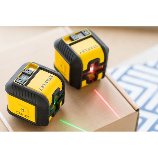 STANLEY STHT77648-1 laser levels, yellow and black, projecting red and green lines, close-up photo.