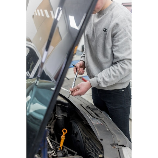 Photo of person using STANLEY STHT80872-0 ratchet wrench on car engine in garage.