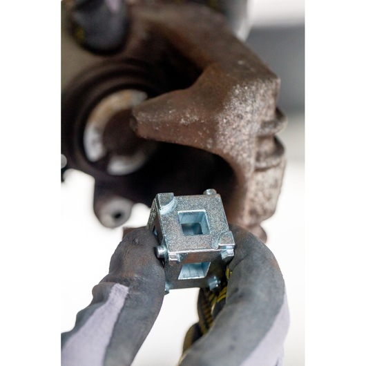 STANLEY STHT80883-0 cube socket tool held by gloved hand near automotive part, close-up photography.