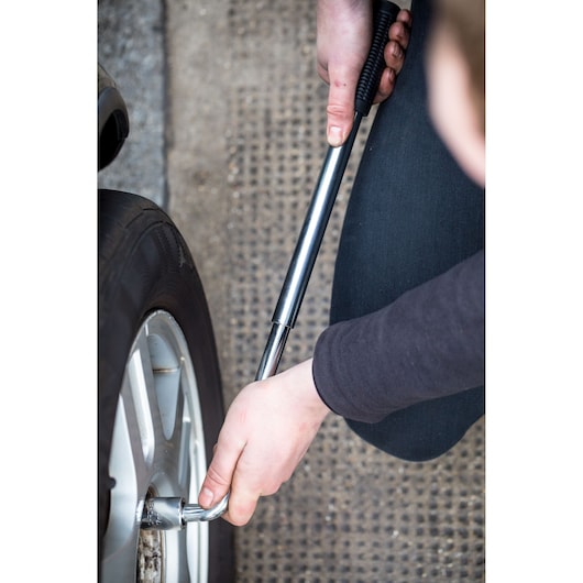 STANLEY STHT80890-0 telescopic lug wrench used to loosen a car wheel nut, close-up photography.